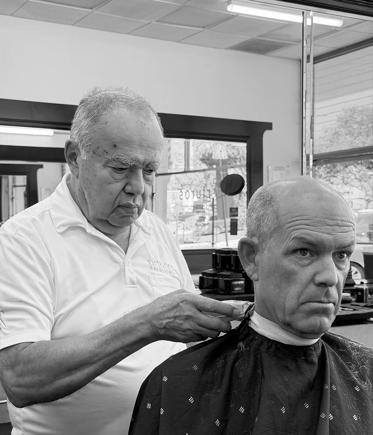 Arturo cutting a longtime client's hair at his Santa Barbara barbershop