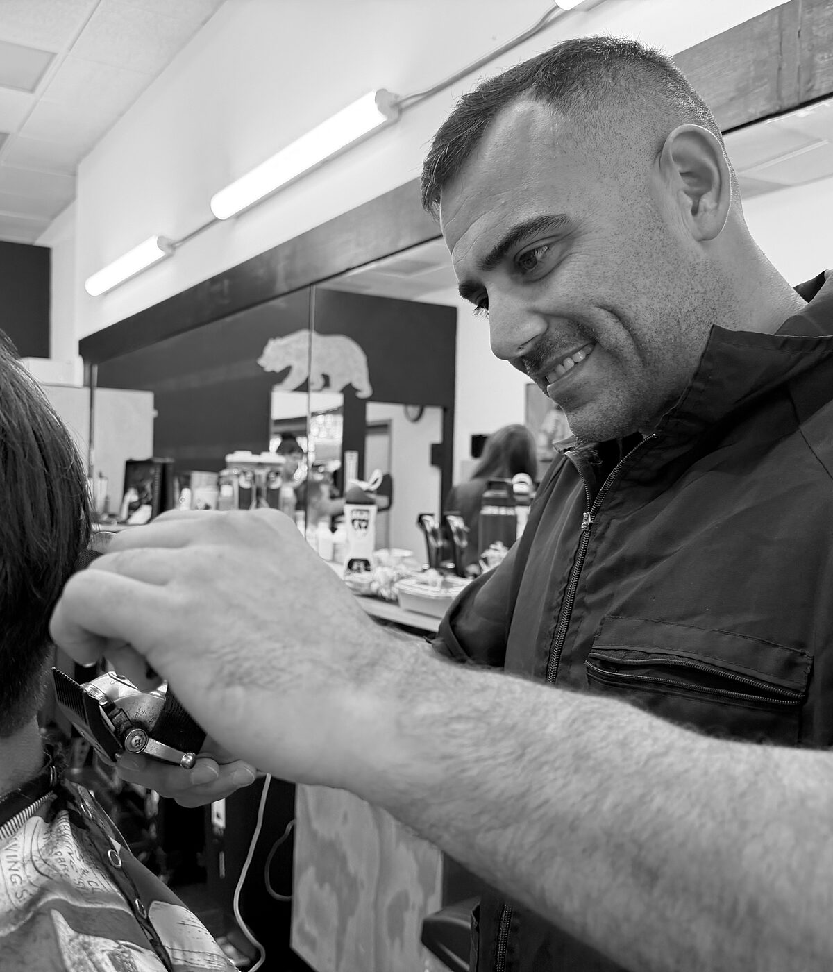 Barber Joseph cutting a client's hair at his station in Arturo's Barbershop