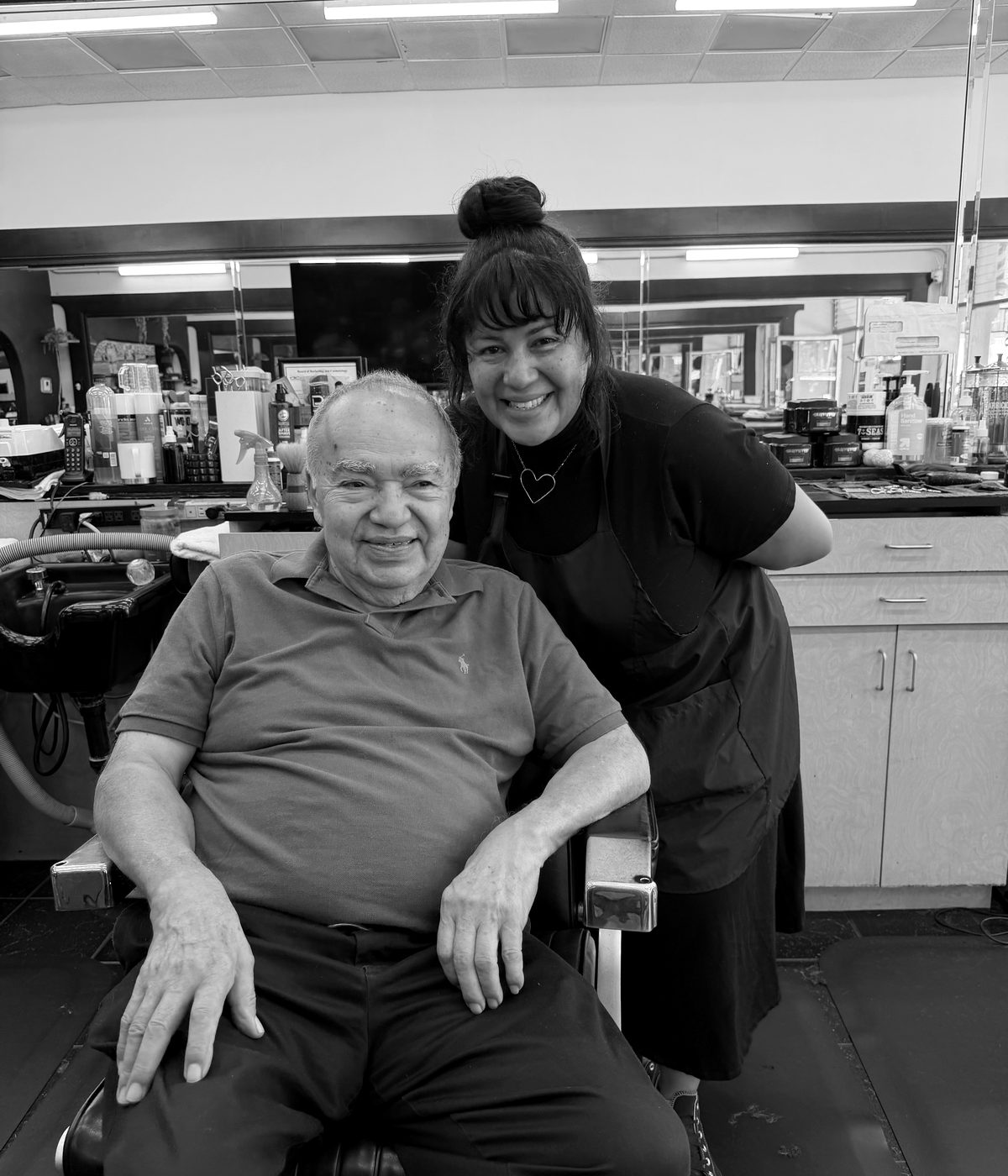 Arturo seated in his barber chair with his daughter Karina at Arturo's Barbershop in Santa Barbara