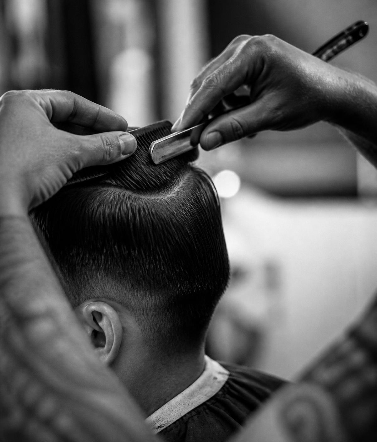 Barber shaping a haircut with comb and straight razor